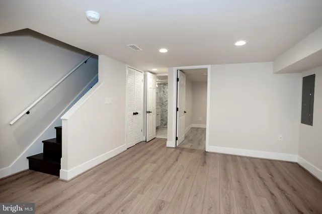a view of an empty room with wooden floor and stairs
