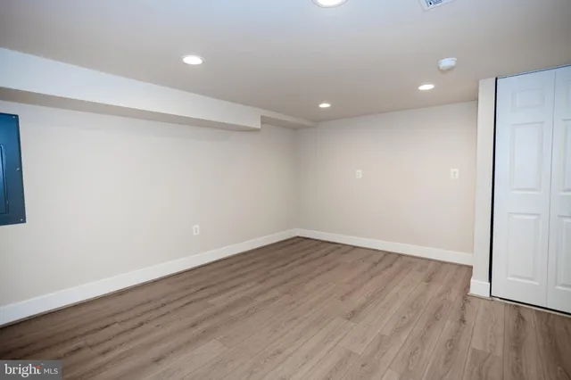 a view of an empty room with wooden floor and closet