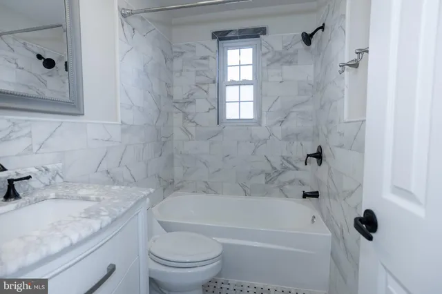 a bathroom with a granite countertop bathtub shower sink vanity and toilet