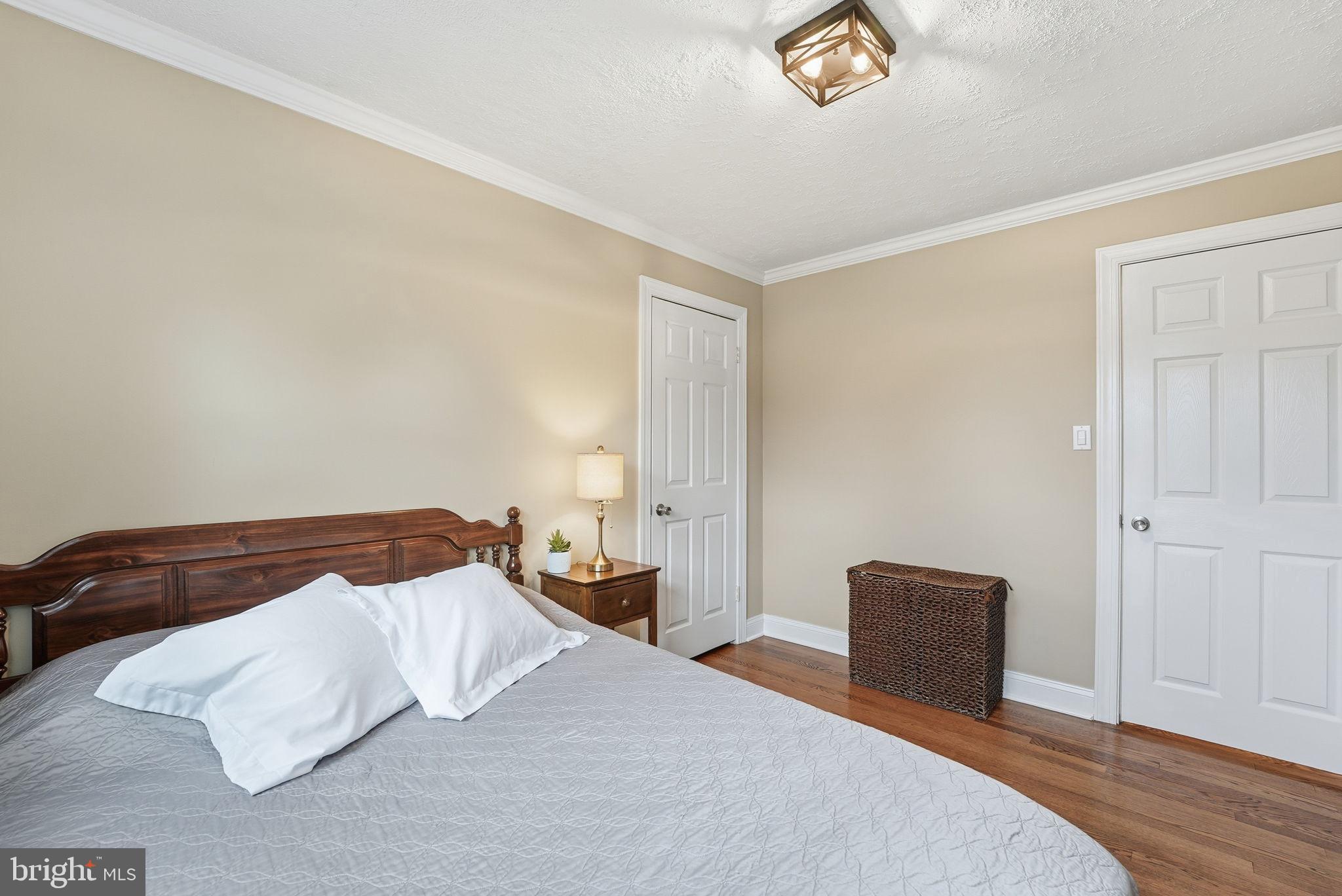 6803 Derrell Court Alexandria, VA 22307 - Photo 19 of 43 a bedroom with a bed and a lamp with wooden floor