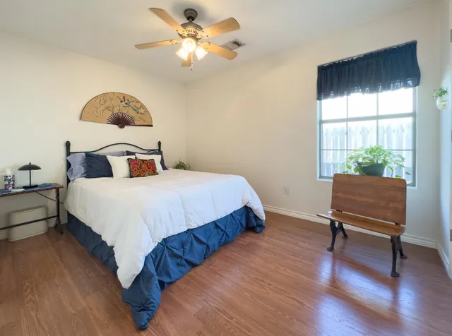 a bedroom with a bed a chair and a large window
