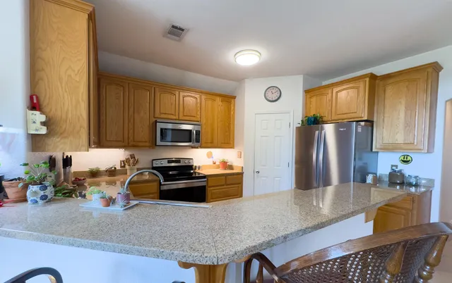 a kitchen with granite countertop a refrigerator a stove top oven a sink and dishwasher