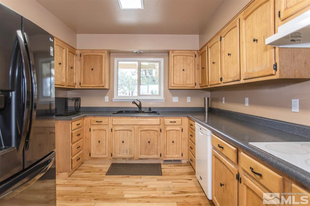 13965 Rancheros Drive Reno, NV 89521 - Photo 5 of 25 a kitchen with granite countertop a refrigerator sink and white cabinets