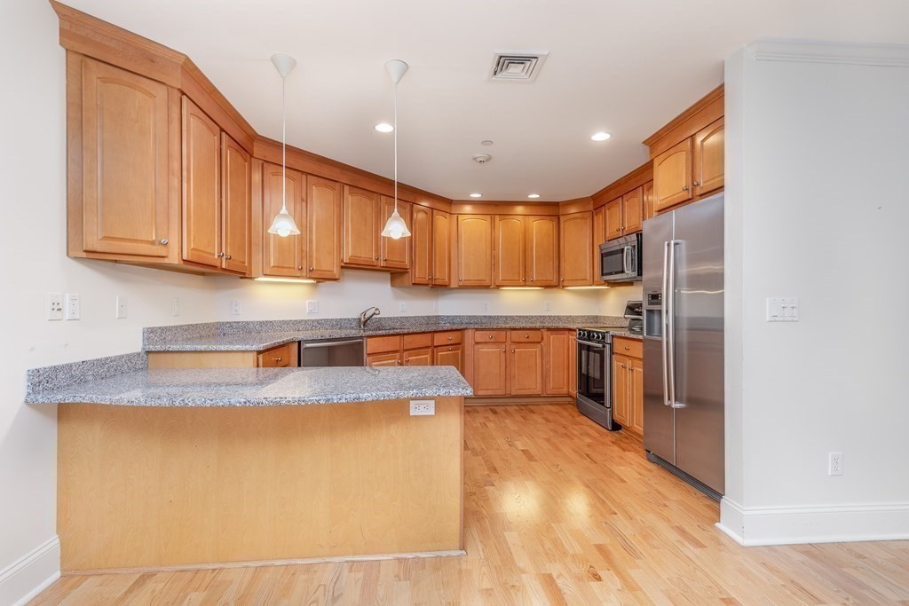 220 Humphrey Street, Unit 204 Marblehead, MA 01945 - Photo 4 of 29 a kitchen with stainless steel appliances granite countertop a sink a stove a refrigerator with grey cabinets