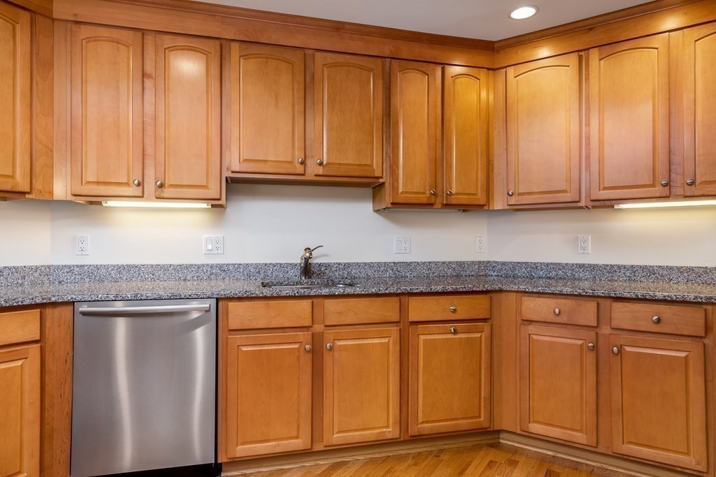 220 Humphrey Street, Unit 204 Marblehead, MA 01945 - Photo 6 of 29 a kitchen with granite countertop a sink a cabinetry and a wooden floor