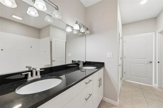 a bathroom with a granite countertop double vanity sink and a mirror