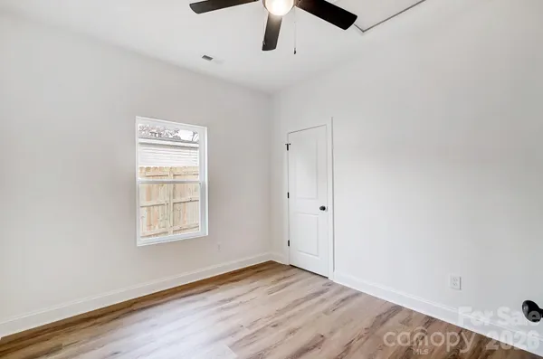 an empty room with wooden floor cabinet and windows