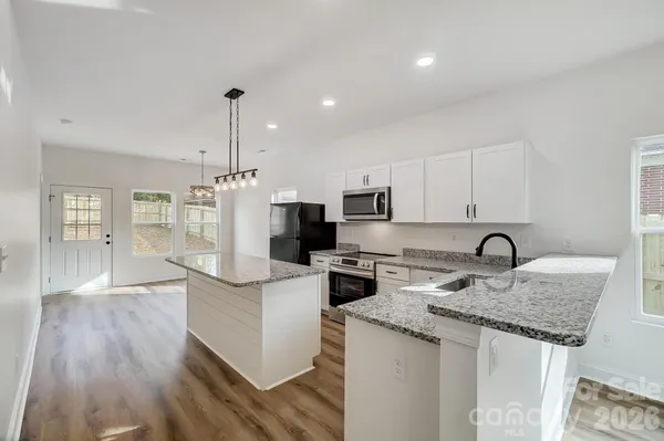 a kitchen with kitchen island granite countertop a sink and refrigerator