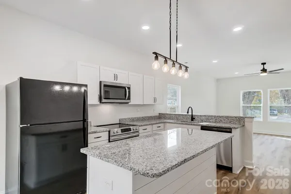 a kitchen with stainless steel appliances granite countertop a sink a refrigerator and a granite counter tops