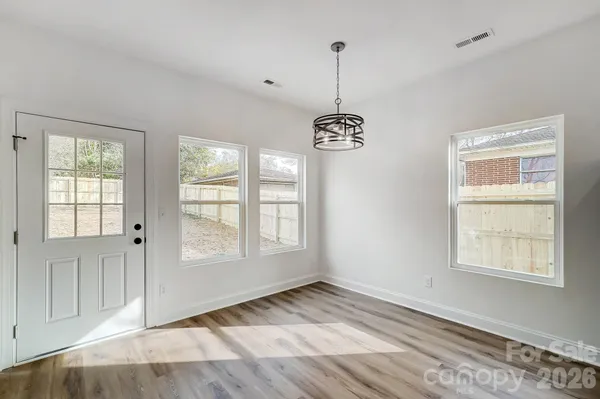 a view of an empty room with window and chandelier fan