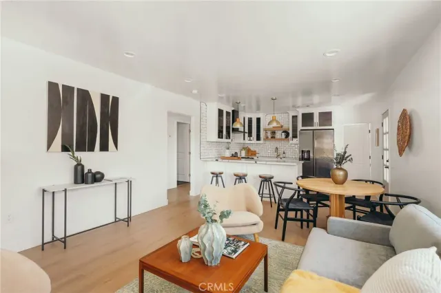 a kitchen with stainless steel appliances kitchen island granite countertop a table chairs in it and white cabinets