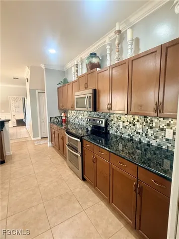 a large kitchen with stainless steel appliances kitchen island granite countertop a refrigerator and stove