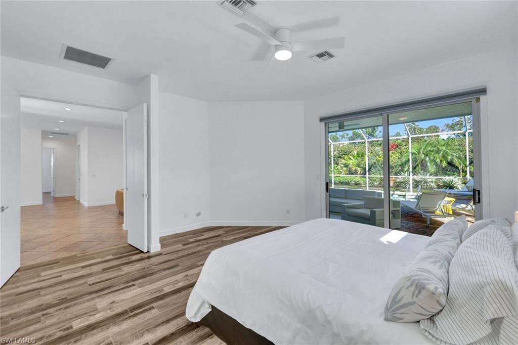 874 Wyndemere Way Naples, FL 34105 - Photo 16 of 32 a bedroom with a bed and wooden floor