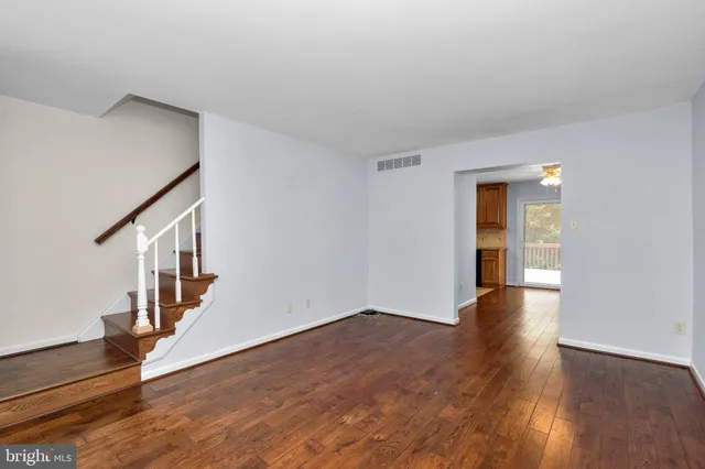 a view of an empty room with wooden floor and stairs