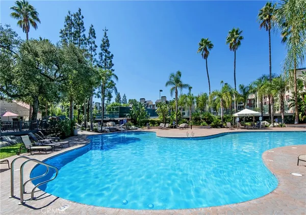 a view of a swimming pool with lawn chairs under an umbrella