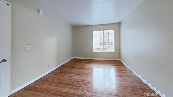 a view of an empty room with wooden floor and window