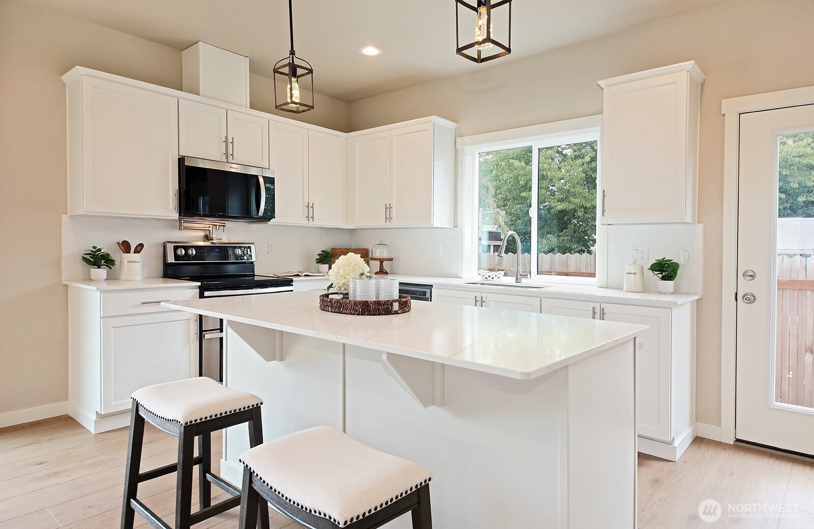 695 3rd Street, Unit B Langley, WA 98260 - Photo 9 of 28 a kitchen with stainless steel appliances a sink a stove a microwave a refrigerator a dining table and chairs with wooden floor