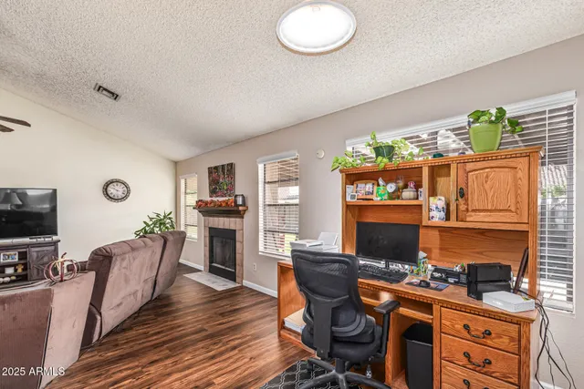 a work room with furniture a flat screen tv and a fireplace