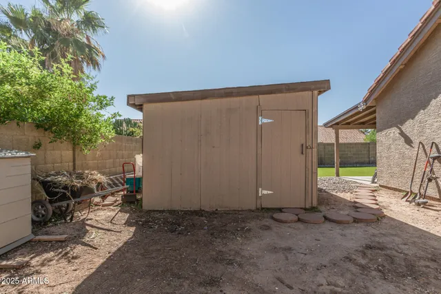 a front view of a house with a dirt yard and a car parked side of road