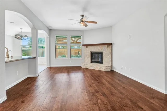 an empty room with wooden floor a fireplace and windows