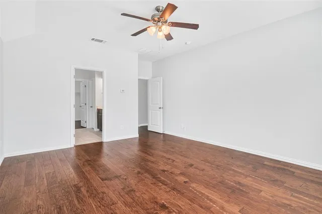 a view of a big room with wooden floor and a ceiling fan