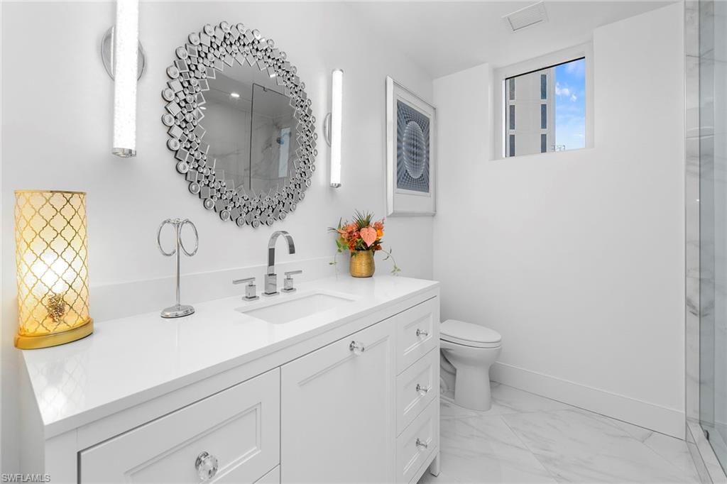 13945 Old Coast Road, Unit 806 Naples, FL 34110 - Photo 28 of 50 a bathroom with a sink mirror vanity and toilet
