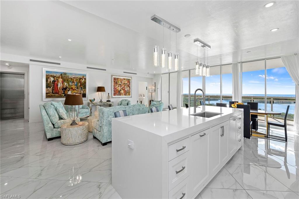 13945 Old Coast Road, Unit 806 Naples, FL 34110 - Photo 49 of 50 a large white kitchen with a white countertops a stove a dining table and chairs