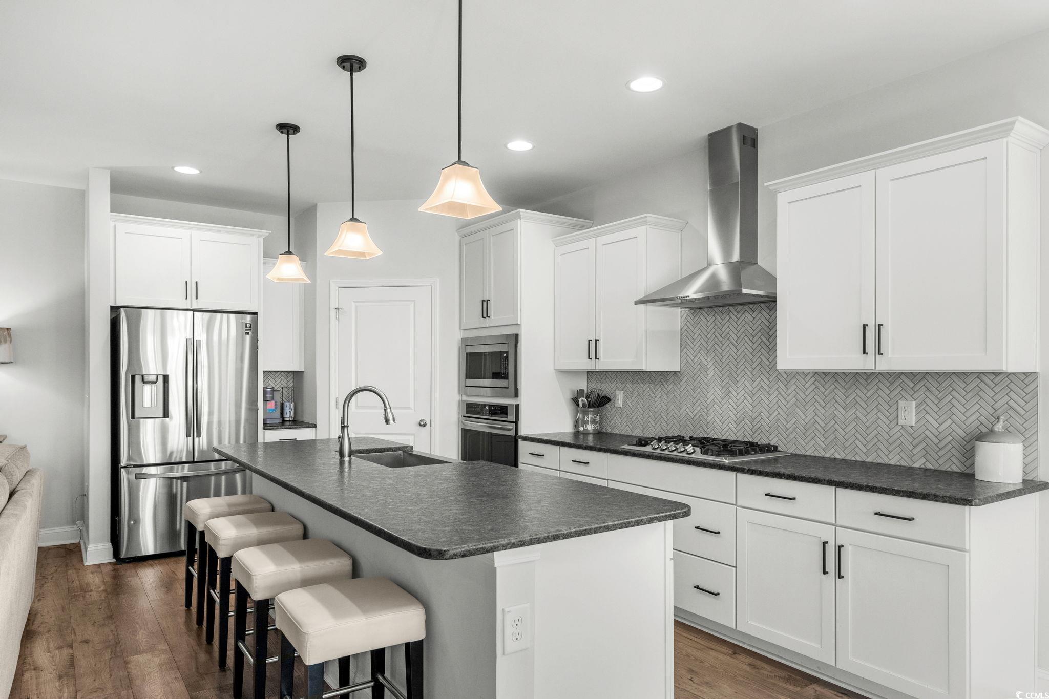 506 Indigo Bay Circle Myrtle Beach, SC 29579 - Photo 13 of 40 Kitchen featuring stainless steel appliances, dark countertops, backsplash, wall chimney range hood, and recessed lighting