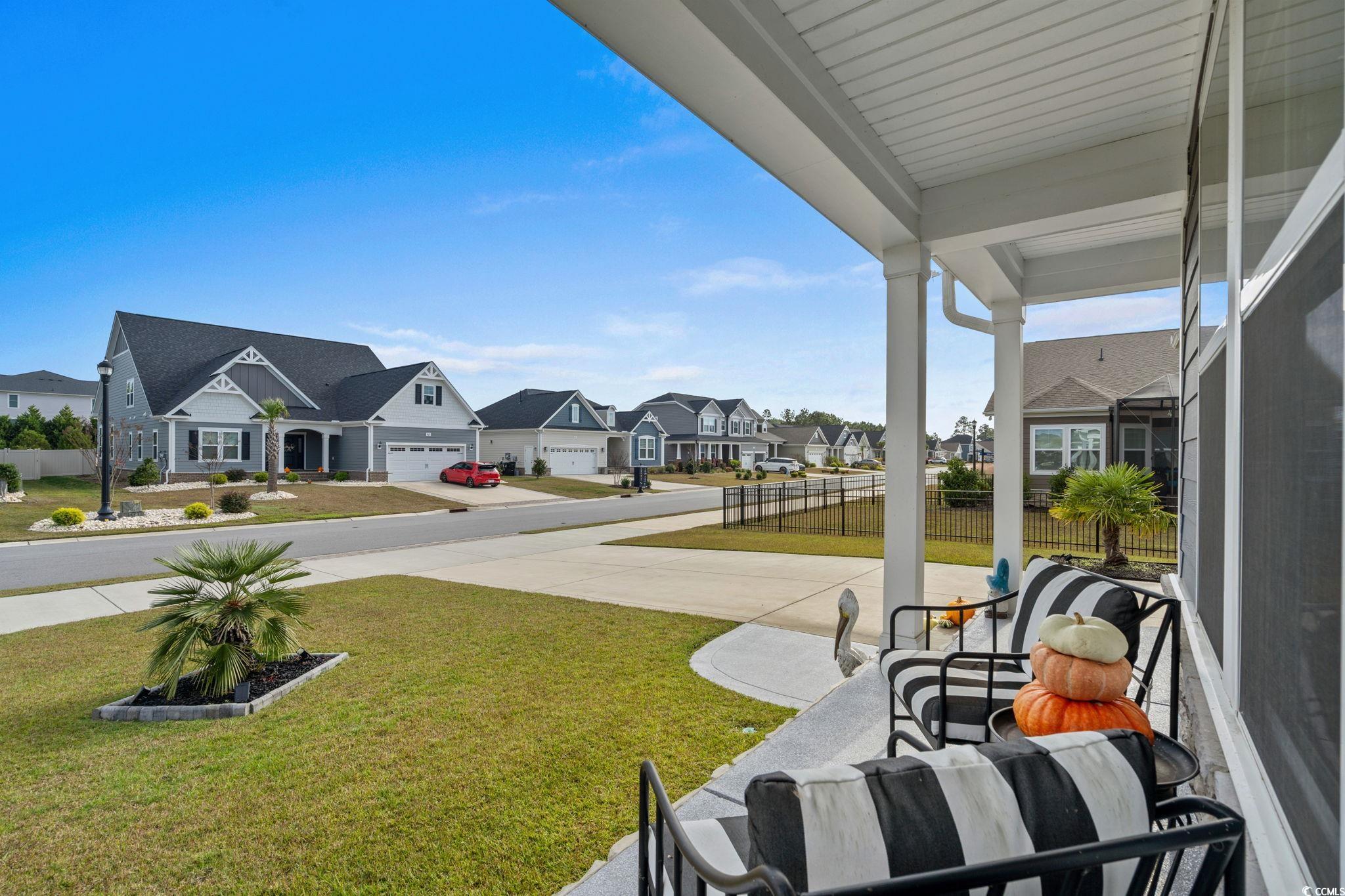 506 Indigo Bay Circle Myrtle Beach, SC 29579 - Photo 5 of 40 View of green lawn featuring a residential view, covered porch, and concrete driveway
