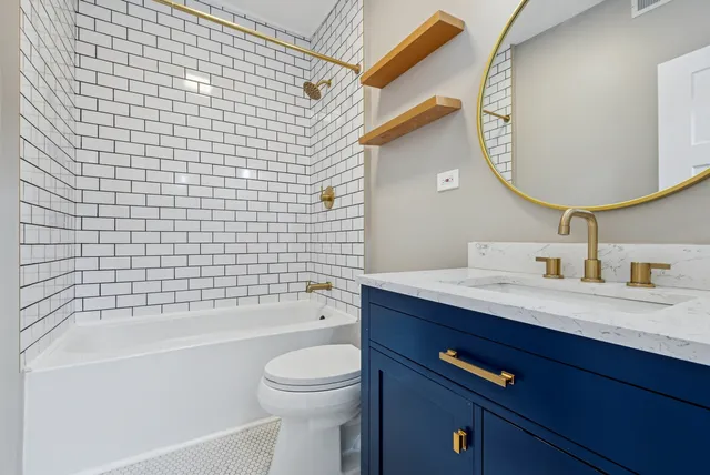 a bathroom with a bathtub sink vanity mirror and toilet