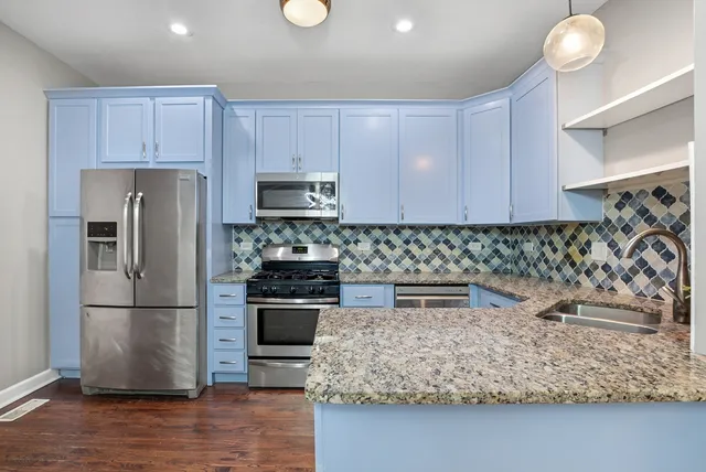 a kitchen with kitchen island granite countertop a sink cabinets and stainless steel appliances