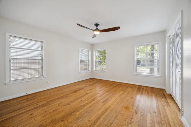 a view of empty room with wooden floor and fan
