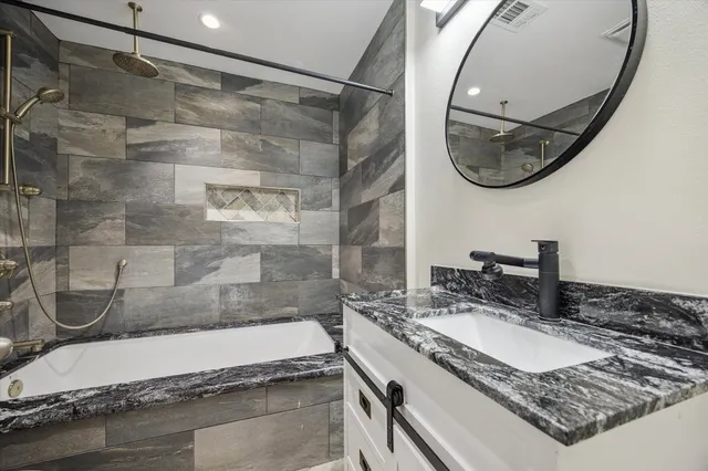 a bathroom with a granite countertop sink mirror and bathtub