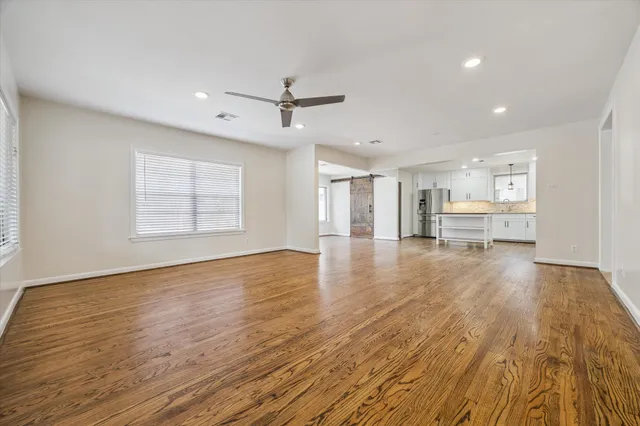 a view of an empty room with a window and wooden floor