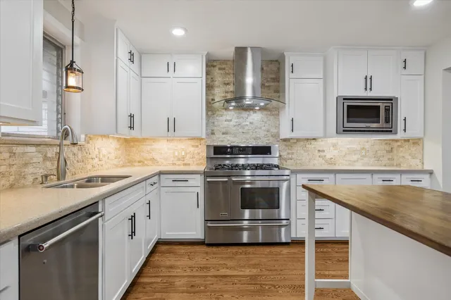 a kitchen with stainless steel appliances granite countertop a stove a sink and a microwave