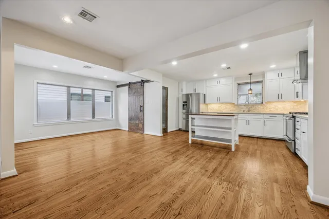 a view of an empty room with a window and wooden floor