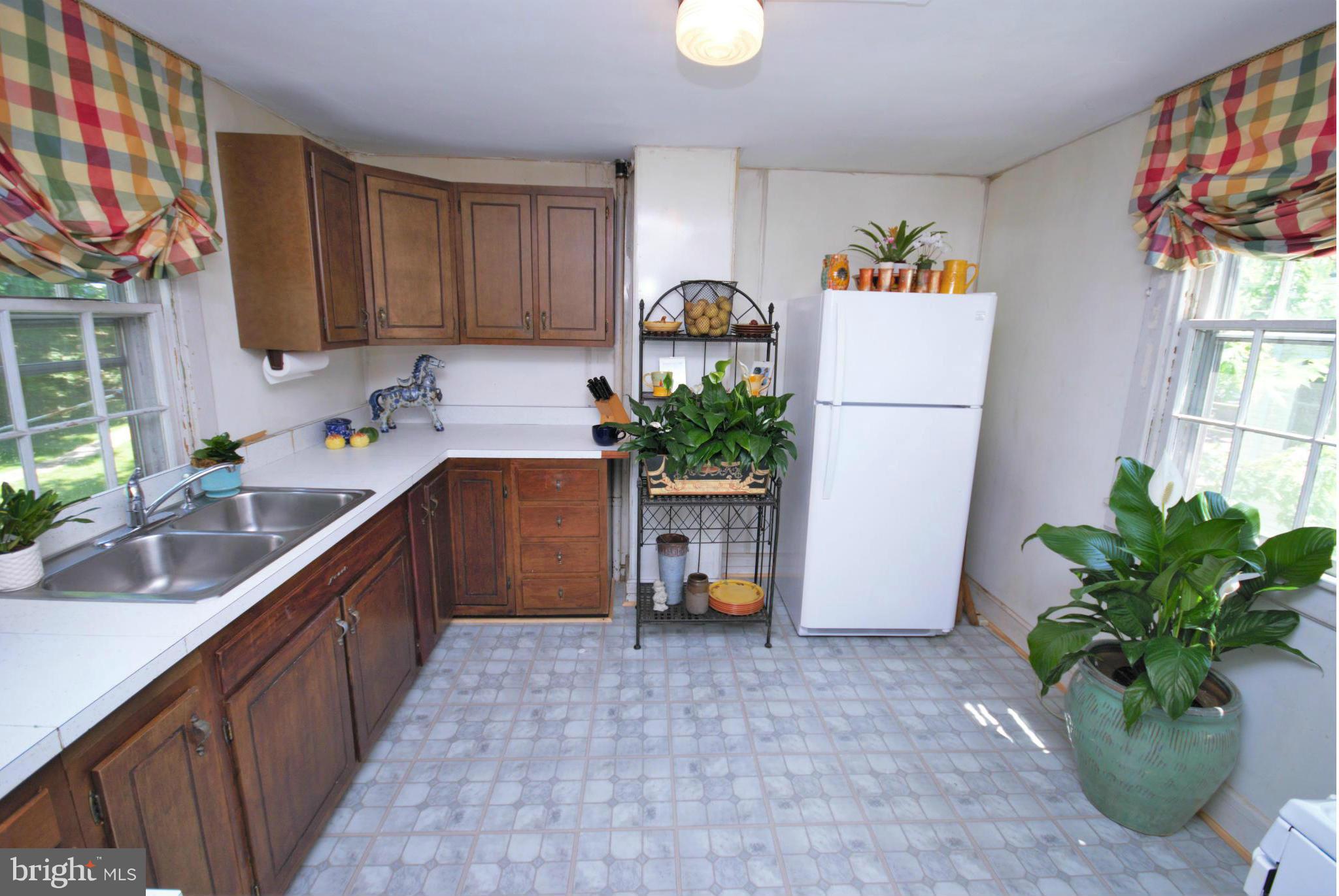 6109 Falls Road Baltimore, MD 21209 - Photo 11 of 26 a kitchen with stainless steel appliances a sink a potted plant and a refrigerator