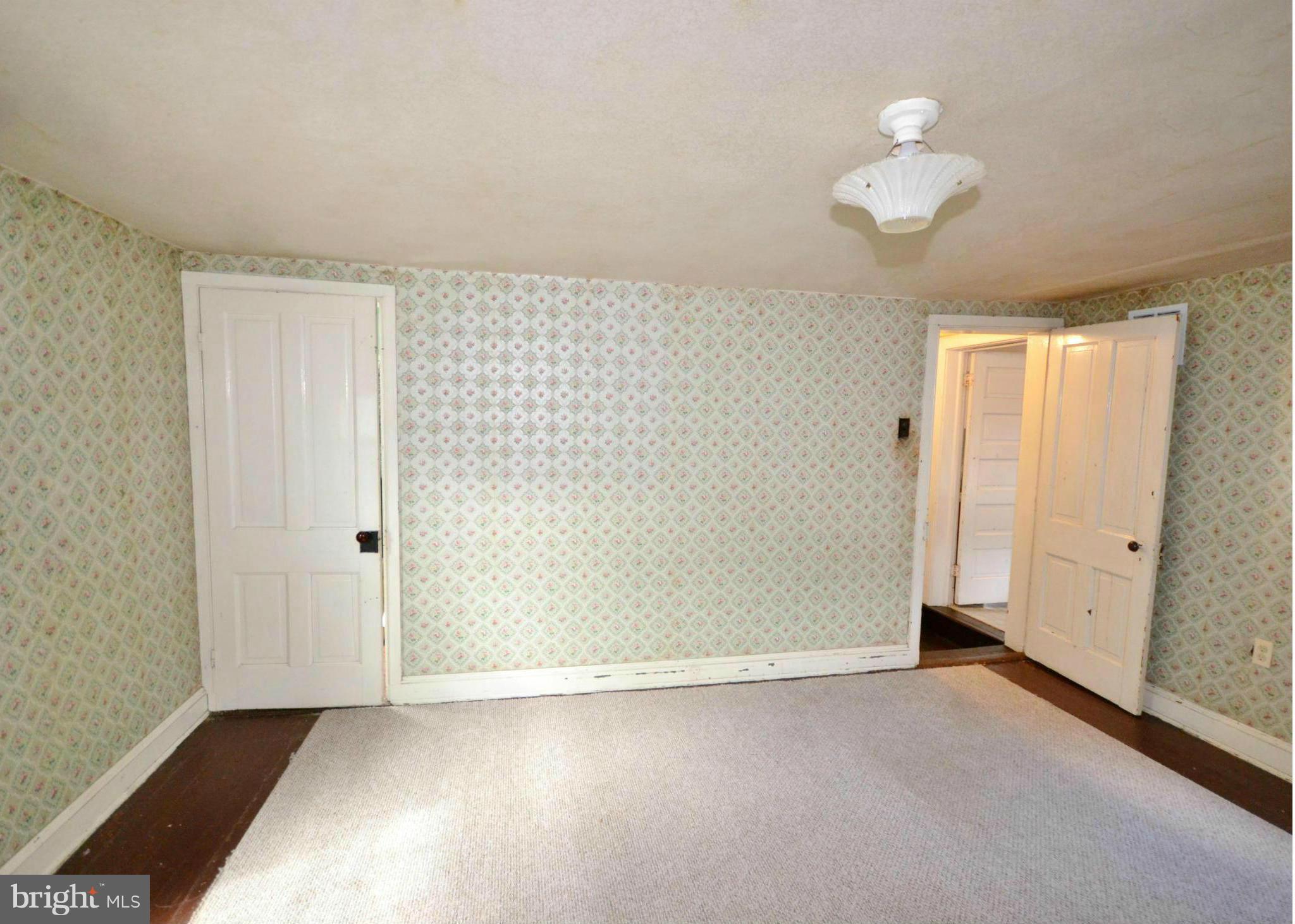 6109 Falls Road Baltimore, MD 21209 - Photo 20 of 26 an empty room with a chandelier fan and wooden floor