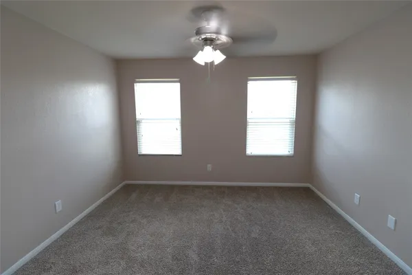 a view of an empty room and chandelier fan