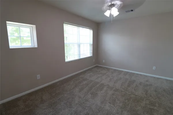 an empty room with windows and chandelier fan