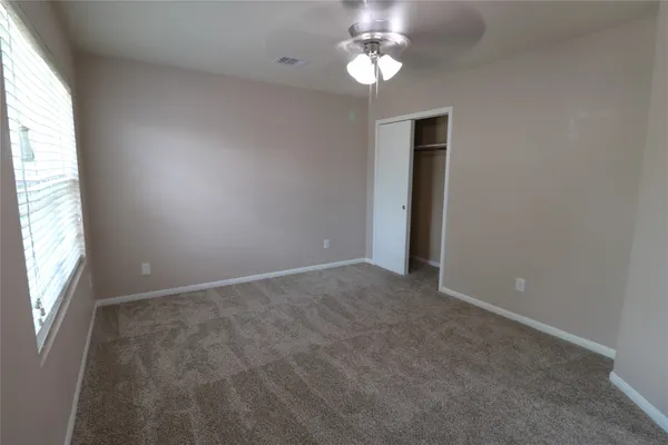 an empty room with windows and chandelier fan