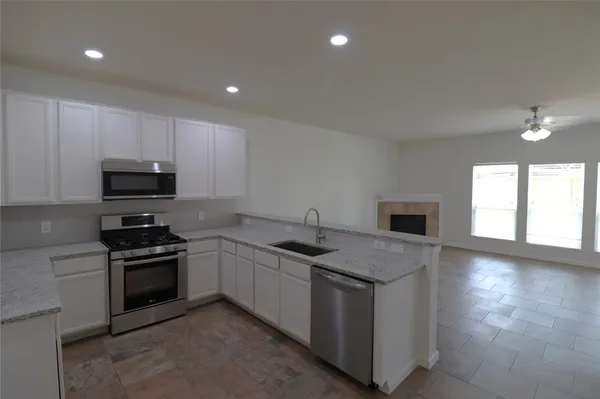 a kitchen with stainless steel appliances granite countertop a stove a sink and a microwave