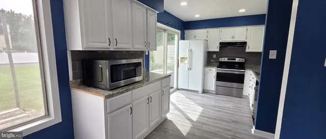 a kitchen with stainless steel appliances granite countertop a stove a refrigerator and a microwave