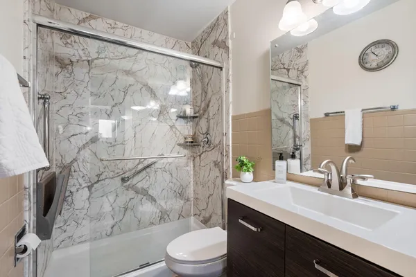 a bathroom with a sink a toilet a mirror and shower