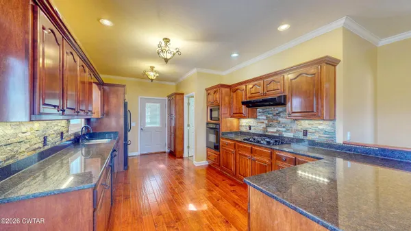 a kitchen with stainless steel appliances granite countertop sink stove refrigerator and cabinets