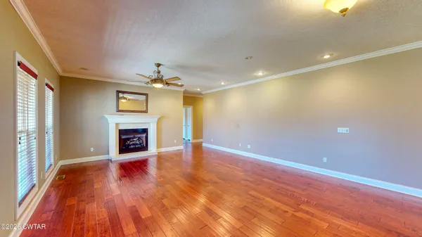an empty room with wooden floor fireplace and windows