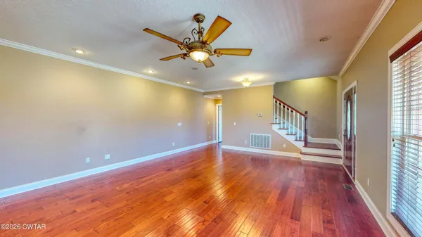 a view of an empty room with window and wooden floor