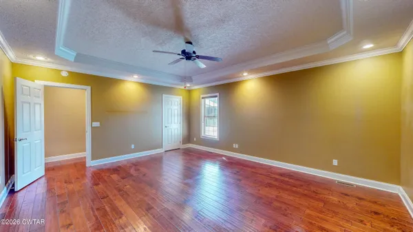 a view of empty room with wooden floor and fan