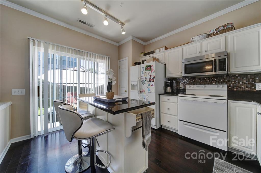 11428 Grove Point Road Charlotte, NC 28277 - Photo 8 of 36 a kitchen with stainless steel appliances granite countertop a stove a refrigerator a microwave a sink and white cabinets with wooden floor