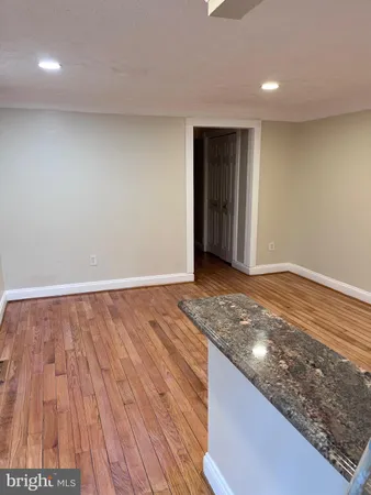 a view of an empty room with wooden floor and closet